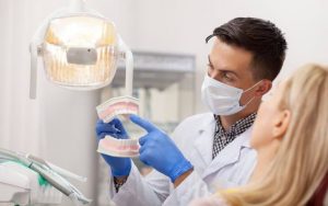 A dentist with a dental model explaining his patient bone graft procedure.