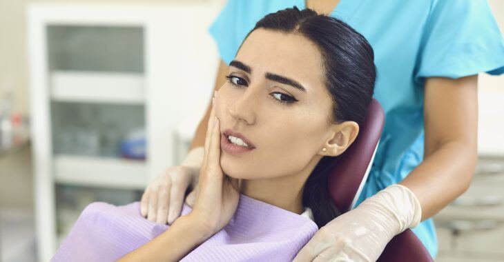 A woman with dental pain in a dental chair before root canal treatment.