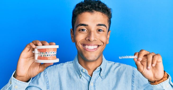 A teenage boy holding braces for overbite correction.