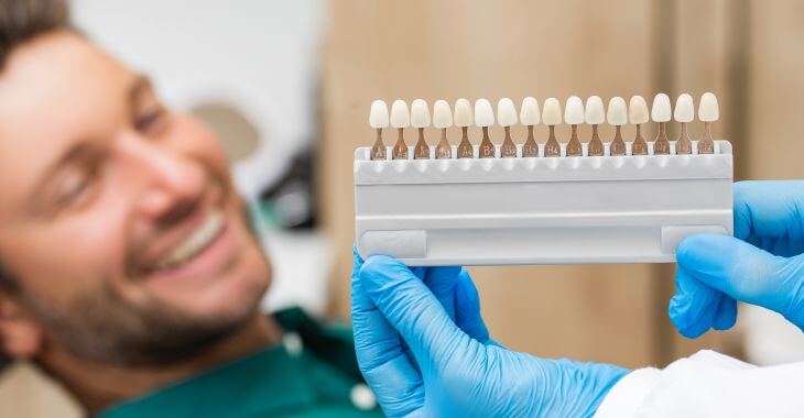 A happy man in a dental chair during veneer color matching.