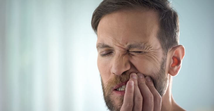 A man with dental pain caused by gum disease.