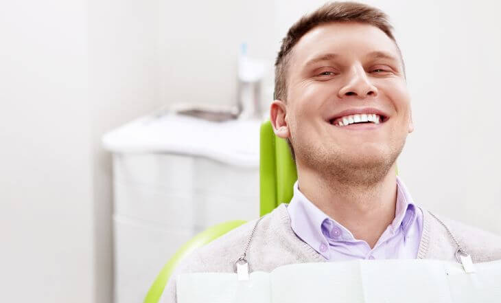 A happy man in a dental chair after dental veneers procedure. 