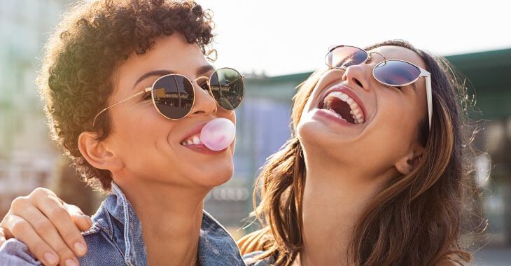 Two happy young women chewing gum.