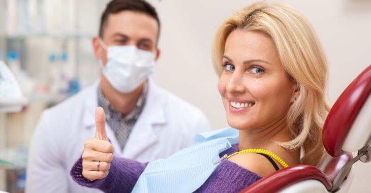 A satisfied woman after dental crown procedure showing her thumb up.