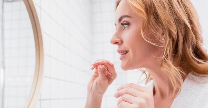 Woman looking at her teeth in the mirror while teeth cleaning.