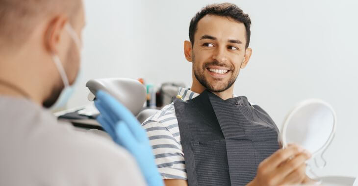 A satisfied man after dental crown procedure talking to a dentist.