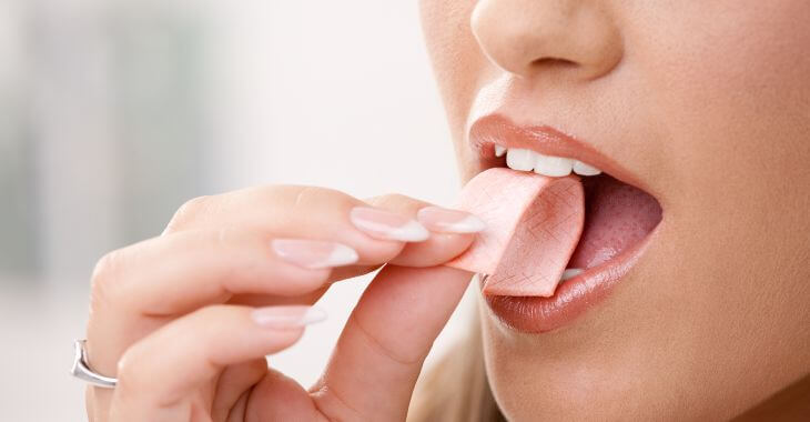 A woman putting chewing gum into her mouth.