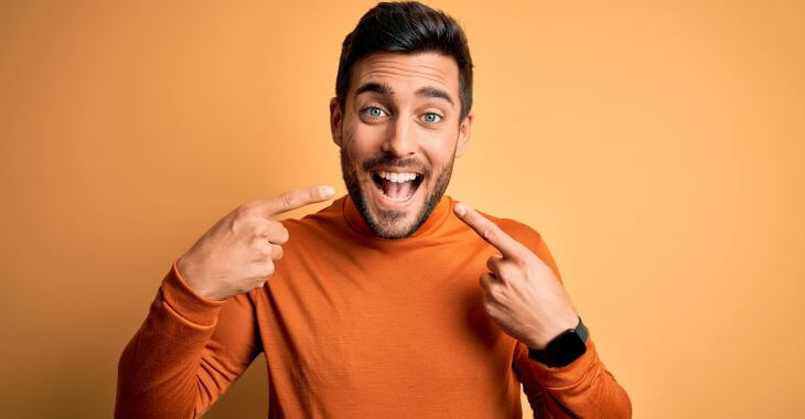 Happy man pointing at his nice healthy teeth.