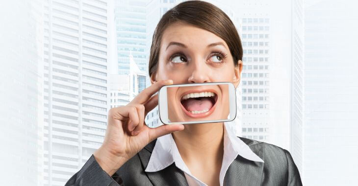 A businesswoman holding a phone with a photo of a perfect smile.