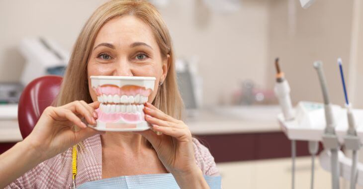 A satisfied mature woman with dental model after dental treatment.