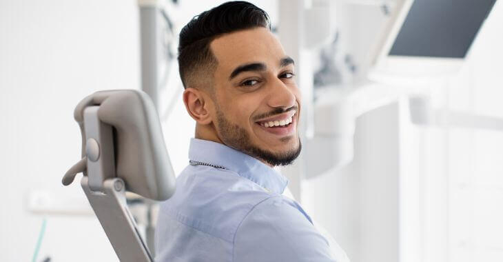 Smiling man with perfect teeth in a dental chair.