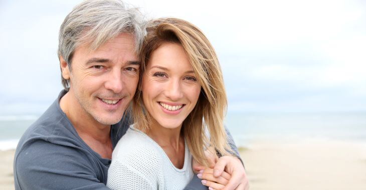 A joyful middle-aged couple with perfect smiles having a walk on the beach.
