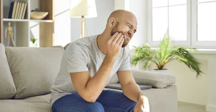 A man suffering from bottom teeth pain.