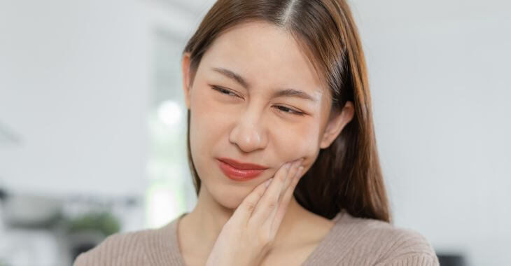 A woman touching her jaw due to dental issue.