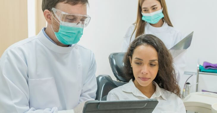 A dentist showing a female patient possible solutions for missing back teeth replacement.