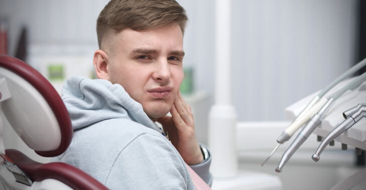 A concerned young man with dental pain at a dentist's office.