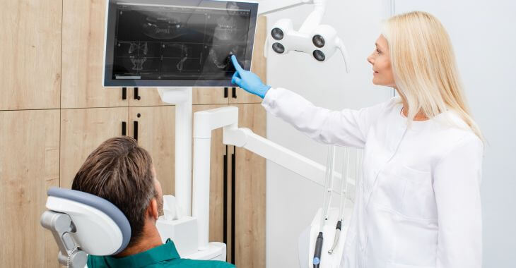 Dentist reviewing man's dental imagings.