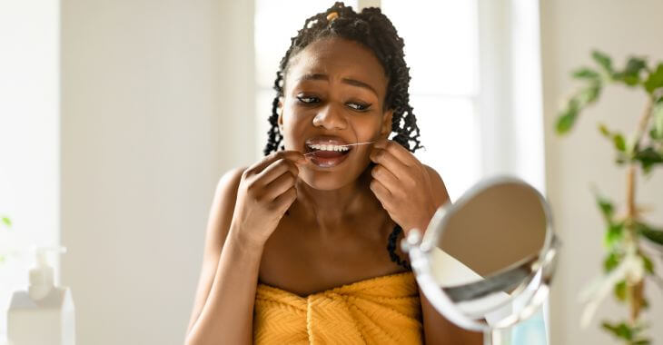 An Afro-American woman flossing her teeth.