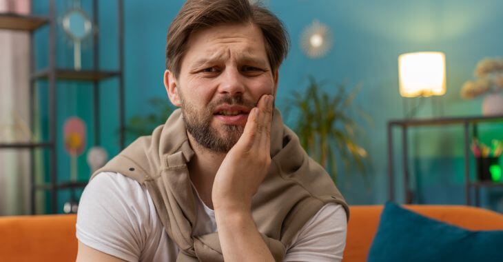 A man feeling pain and discomfort due to a blood blister in his mouth.