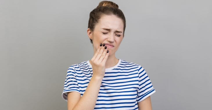 A young woman with pain caused by a blister in her mouth.