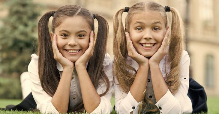 Two cheerful schoolgirls showing nice white teeth in their smiles.