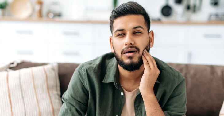 A man touching his cheek and feeling hard bumps on his gum.