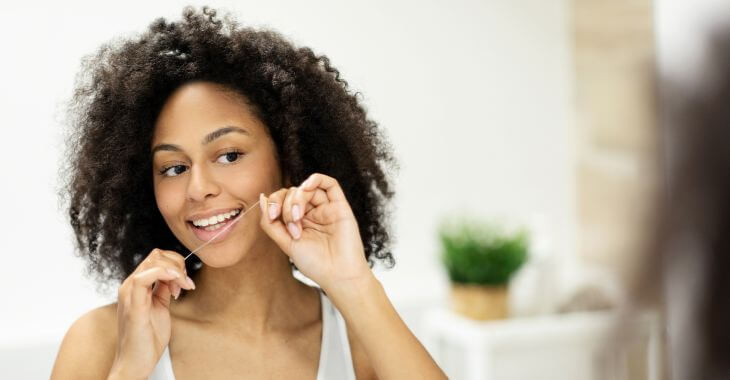 Young Afro-American woman flossing her teeth.