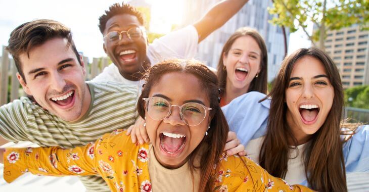 Multicultural group of broadly smiling young people taking selfie