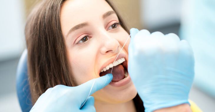 A dentist flossing woman's teeth.