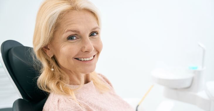 Happily smiling mature woman sitting in a dental chair 