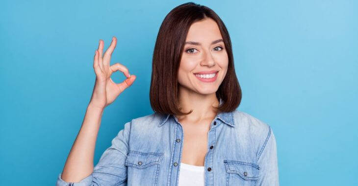 A young woman with a perfect smile showing OK with her fingers