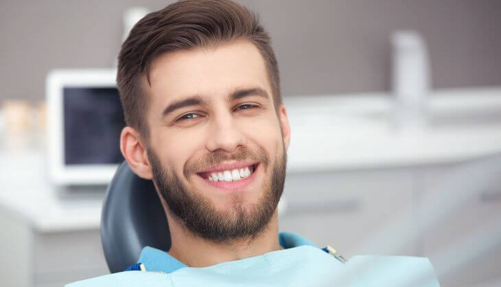 A chherful relaxed young man with a perfect smile sitting in a dental chair after a procedure