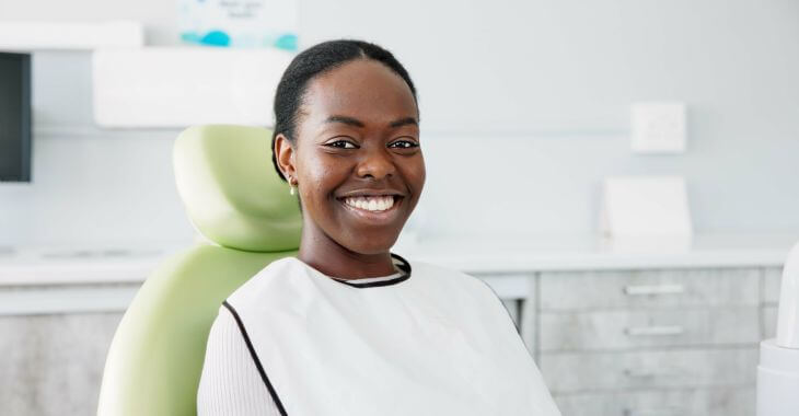 A happily smiling Afro-American woman with nice helathy teeth and gums sitting in a dental chair