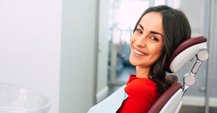 A relaxed smiling woman sitting in a dental chair after waiting for the dentist