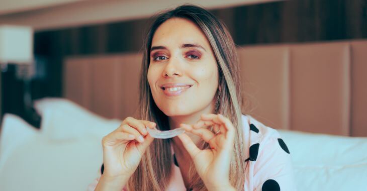 A woman in pygamas with dental night guards getting ready to sleep