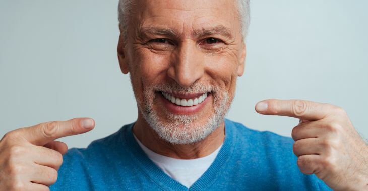 Happy smiling senior man pointing at his perfect smile