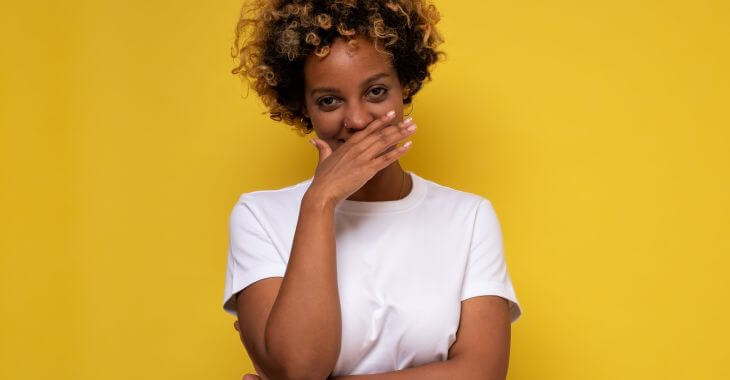 An Afro-American woman covering her mouth with hand while smiling